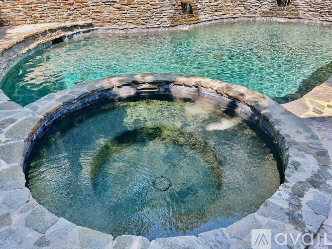 A stone fountain in the middle of a pool.