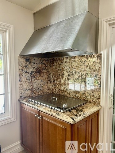 A kitchen with a granite countertop and a stainless steel range hood.