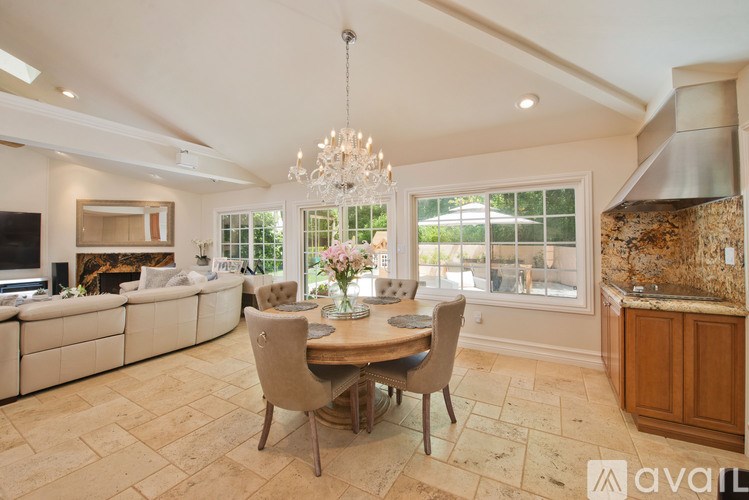 A dining room with a table set for four and a chandelier hanging from the ceiling.
