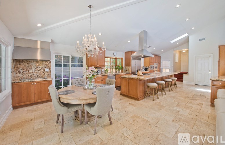 A spacious kitchen with a dining table set up with chairs.