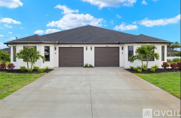 A two-car garage with a white house and brown roof.