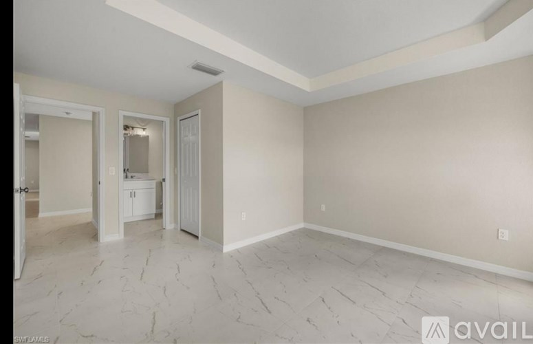 A spacious room with marble flooring and a doorway leading to another room.