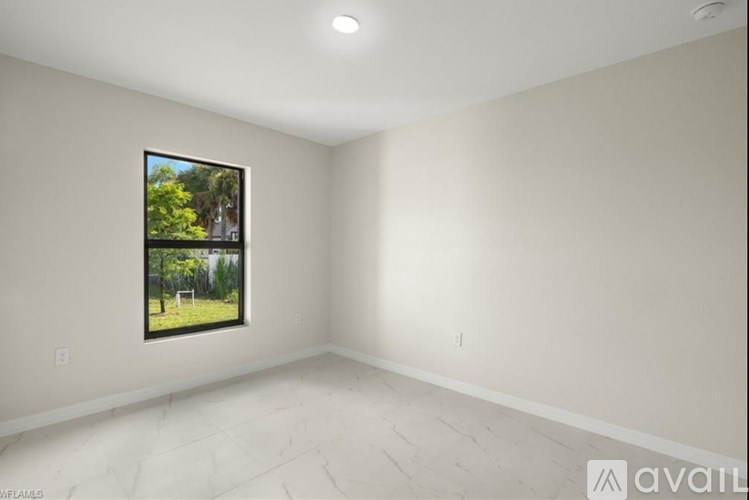 A room with a window showing a tree and a fence outside.