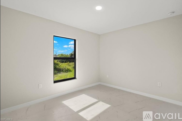 A room with a large window showing a view of a green landscape.