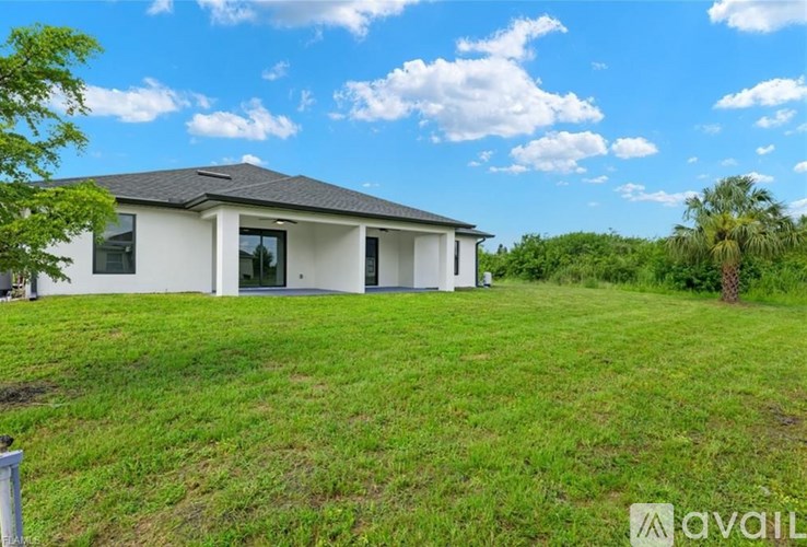 A house with a white exterior and a grey roof is surrounded by green grass.