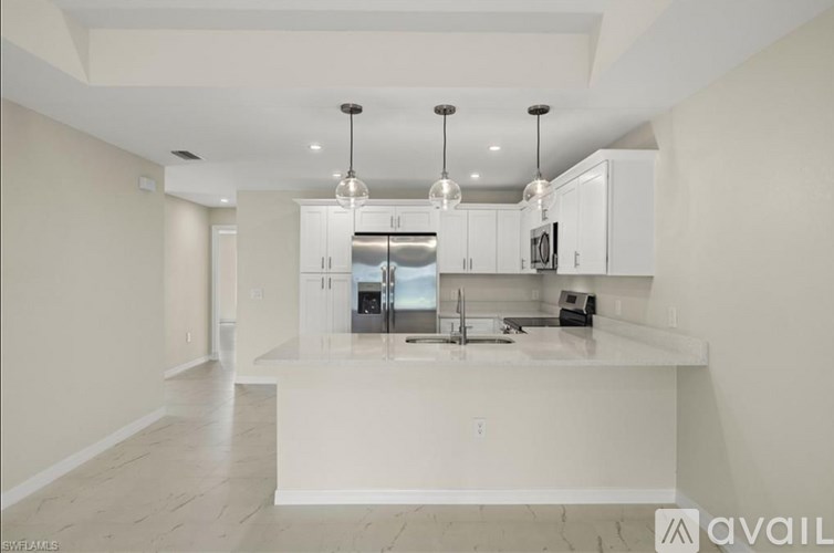 A modern kitchen with white cabinets and a marble countertop.