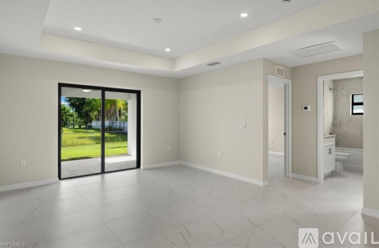 A spacious room with a view of a green lawn through a glass door.