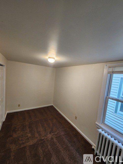 A room with a brown carpet and a window with blinds.