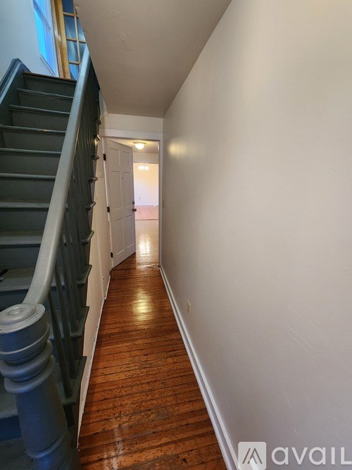 A long hallway with a wooden floor and a staircase on the left.