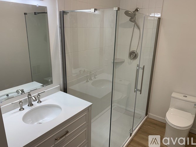 A bathroom with a sink, toilet, and glass shower stall.