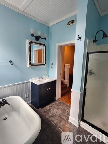 A bathroom with blue walls and a white bathtub.