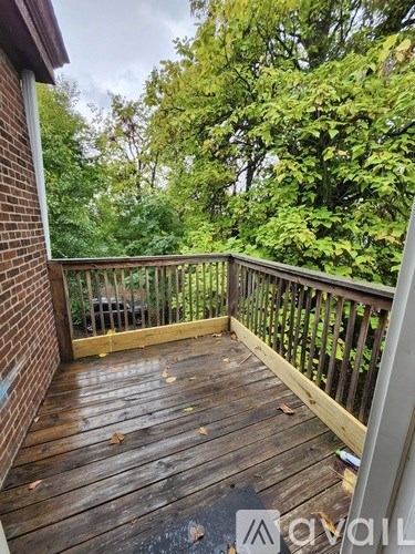 A wooden deck with a railing and trees in the background.