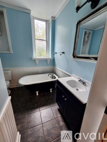 A bathroom with blue walls and a white bathtub.