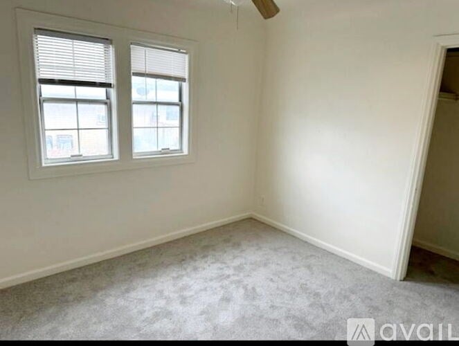 A room with two windows and carpeted floor.