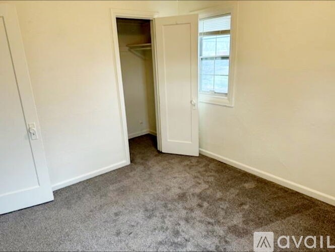 A room with a carpeted floor, a door, and a window.