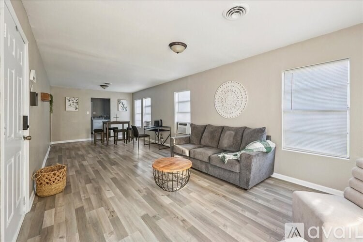 A living room with a grey couch, a wooden coffee table, and a white wall with a circular decoration.