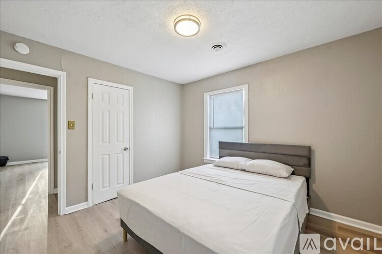 A bedroom with a bed, a window, and a door.