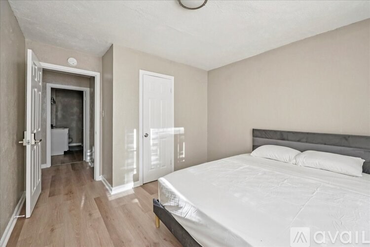 A bedroom with a large bed and a wooden floor.