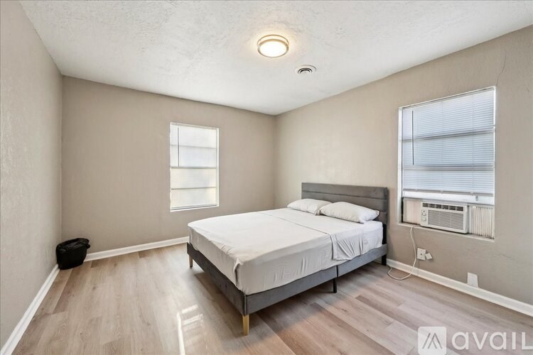 A bedroom with a bed, window, and air conditioner.