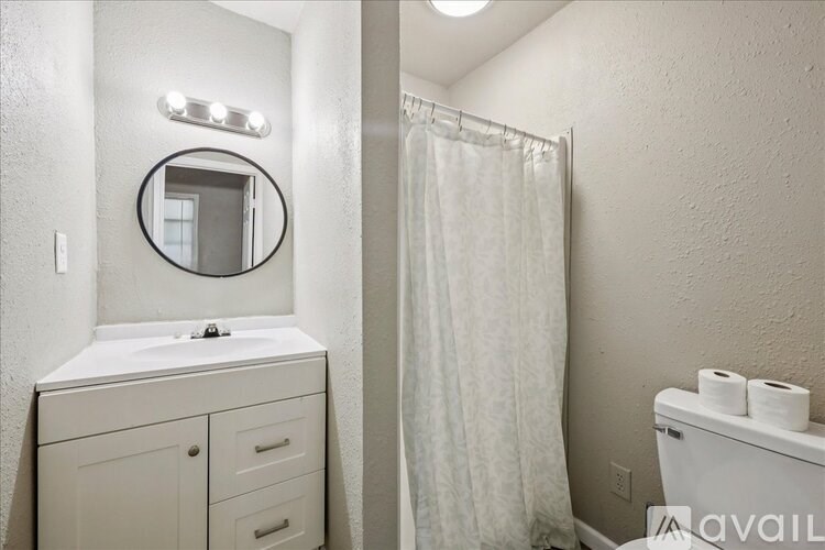 A bathroom with a white sink, mirror, and toilet.