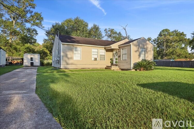 A house with a brown roof and a white fence is surrounded by green grass.
