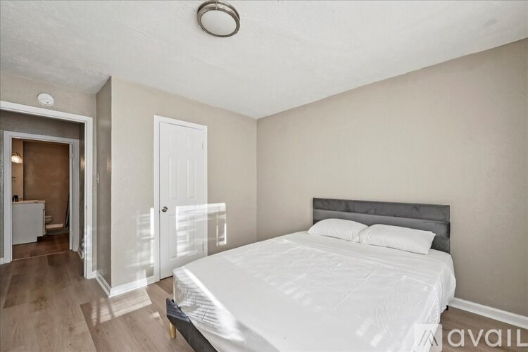 A bedroom with a large bed and a wooden floor.