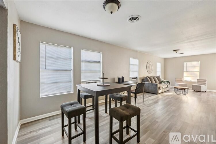 A well-lit room with a dining table and chairs, and a couch in the background.
