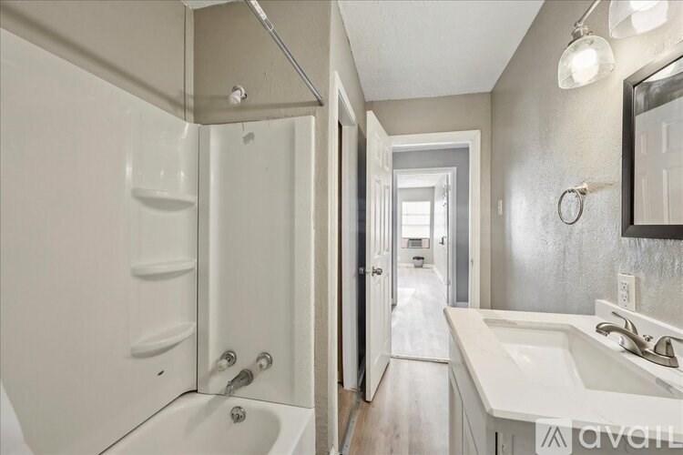 A white bathroom with a tub, sink, and mirror.