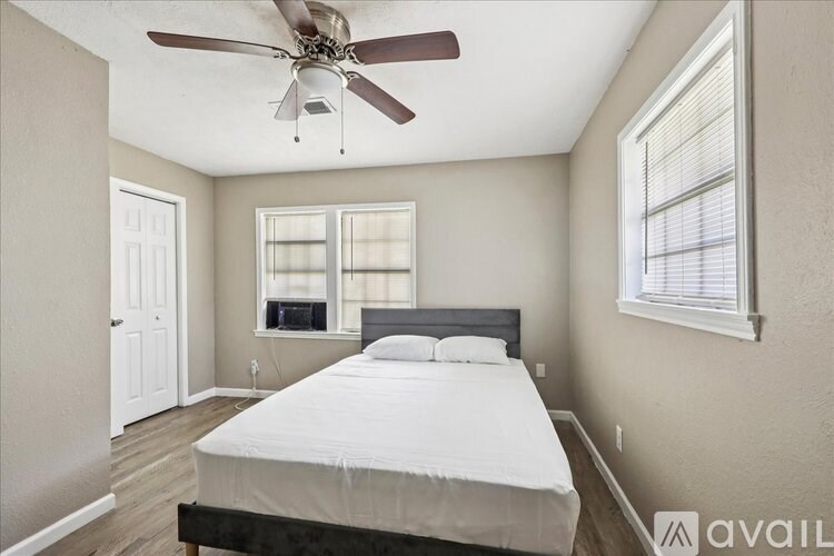 A bedroom with a bed, a ceiling fan, and a window with blinds.