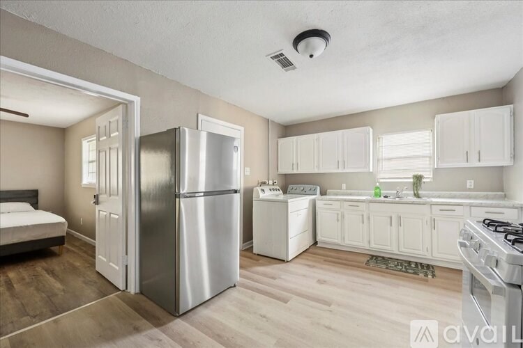 A kitchen with a stainless steel refrigerator and white cabinets.