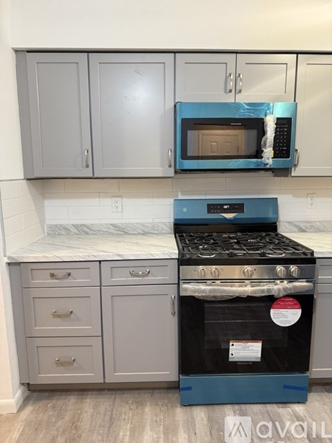 A kitchen with a blue stove and grey cabinets.