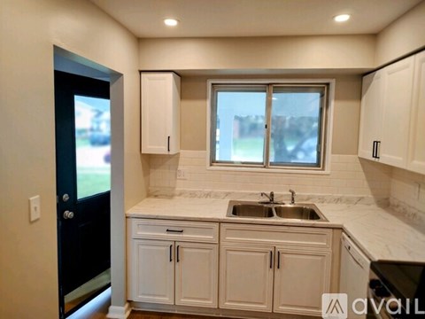 A kitchen with white cabinets and a marble countertop.
