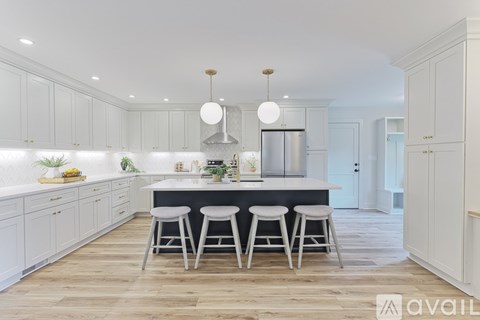 A kitchen with white cabinets and a wooden floor.