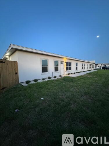 A white house with a wooden fence and grass in front.