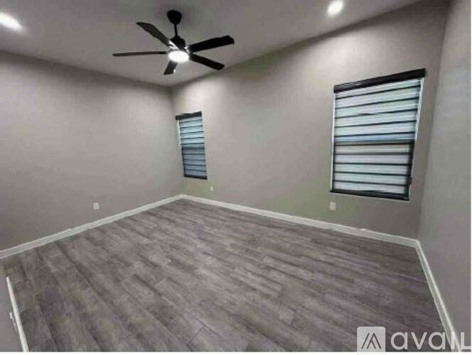 A room with a ceiling fan and a window with blinds.