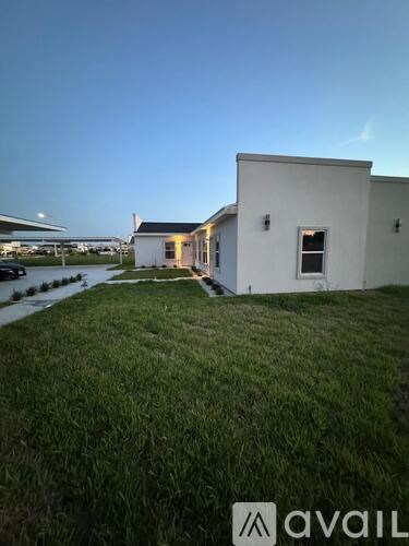 A white house with a dark roof is situated on a grassy area.