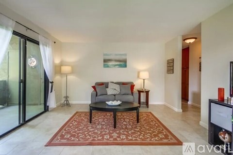 A living room with a grey couch and a red patterned rug.