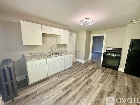 A kitchen with white cabinets and a black fridge.