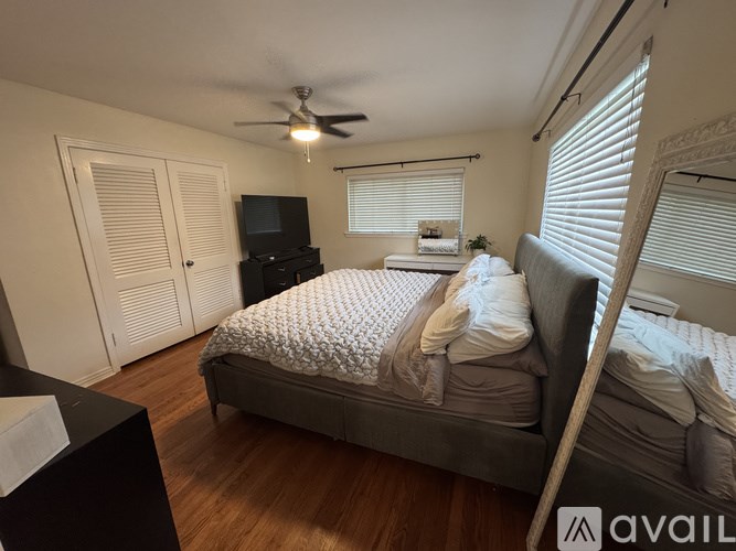 A bedroom with a bed, dresser, and ceiling fan.