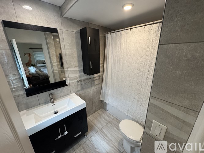 A bathroom with a white sink, black cabinet, and a white toilet.