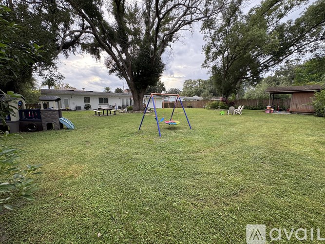 A backyard with a swing set and a tree.