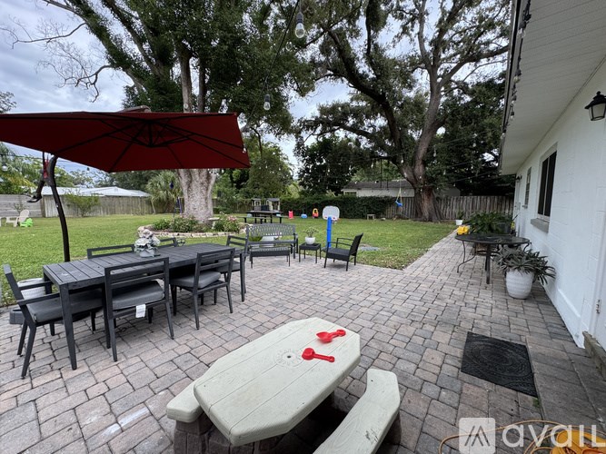 A patio with a table and chairs under a red umbrella.