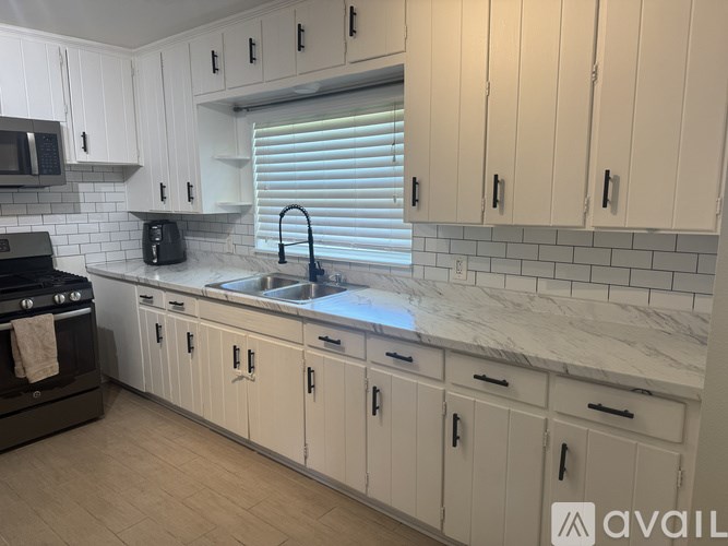 A kitchen with white cabinets and a marble countertop.