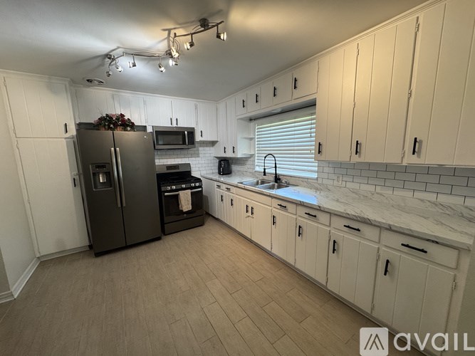 A kitchen with a black refrigerator and white cabinets.