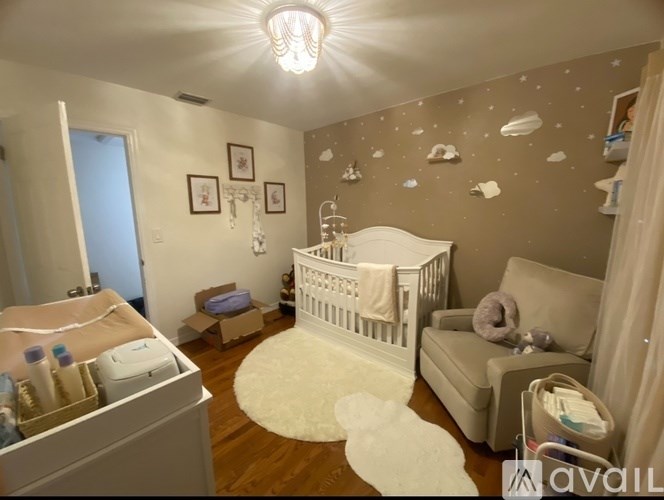 A baby nursery with a white crib, a changing table, and a teddy bear on the floor.