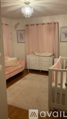 A baby nursery with a crib, changing table, and a pink canopy.