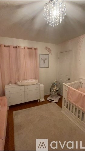 A baby nursery with a crib, changing table, and a chandelier.