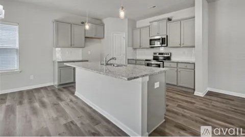 A kitchen with a granite countertop and wooden flooring.