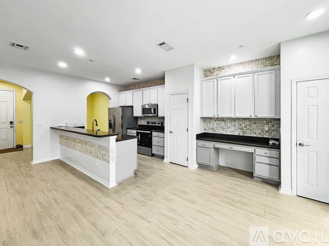 A kitchen with white cabinets and a yellow accent wall.