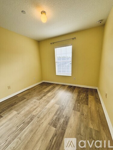 A room with wooden flooring and a window with blinds.